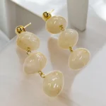ARETES COLGANTES DE BOLAS BLNCAS TIPO CUARZO (CONTIENE ACERO INOXIDABLE)